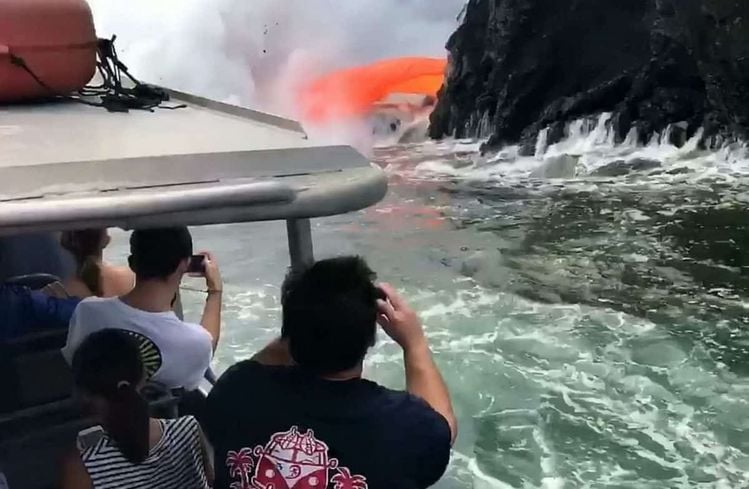 This is the spectacular moment tonnes of molten lava spew from a collapsed volcano into the sea - just yards from boat full of tourists. See SWNS story SWLAVA; Onlookers braved the choppy seas and deadly eruptions taking place at the Kamokuna lava delta in Hawaii since it collapsed on December 31. They were stunned when a red hot stream of 1000c lava suddenly crashed through the side of the black rock - causing an incredible hose pipe effect. Breath-taking footage shows the ''once-in-a-lifetime'' natural phenomenon as hot gunge pours into the sea - solidifying and producing thick clouds of steam. Tour operator Captain Shane Turpin, who shot the footage with guests on his Lava Ocean Tours ship, said: ''This was a real rare sight as the guests watched in awe.