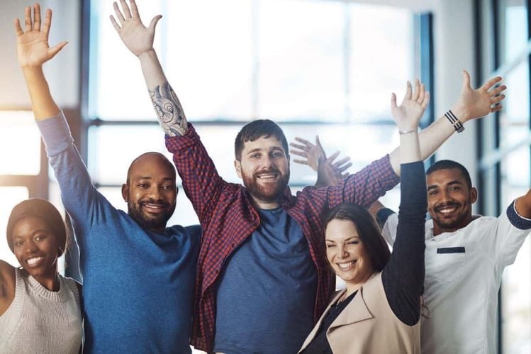 Portrait of a group of young colleagues cheering at work