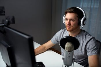 technology, gaming, entertainment, let's play and people concept - happy young man in headset with pc computer playing game at home and streaming playthrough or walkthrough video