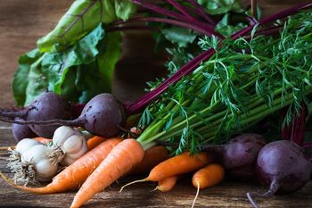 Bunch of fresh organic beetroots, garlic and carrots on wooden rustic table, different types of root vegetables