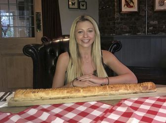 Kate Ovens begins her challenge to eat a saugsauge roll which is - three feet long. See National news story NNROLL; A woman has taken on Britain's biggest sausage roll - measuring a massive 3FT and so big it needs to be served on a FENCE POST. Famous challenge eater Kate Ovens managed to polish off most of the giant snack in just TEN minutes. But the 23-year-old feared she had met her match with the 3750-calorie snack - because she hit 'the wall' with less than six inches of the meaty treat left. The 5ft 5ins eating machine went for a tactical walk for about ten minutes in a bid to free up some more room.