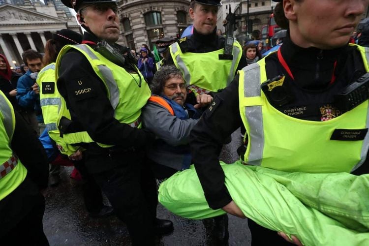 A protester is carried away by police as others block the road in front of the Bank of England (Gareth Fuller/PA)