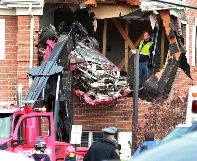 A Porsche is removed form the second story of a building after the convertible went airborne and crashed into the second floor of a New Jersey commercial building early Sunday, killing both of the car's occupants, in Toms River, N.J. (Ed Murray/NJ Advance Media via AP)