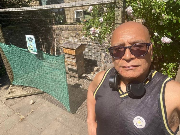 Lee Jasper stands next to the community beehive