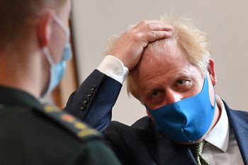 Prime Minister Boris Johnson, wearing a face mask, talks with a paramedic during a visit to the headquarters of the London Ambulance Service NHS Trust.