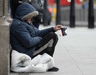 Rough sleeper on street with cup