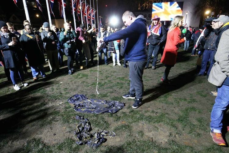 A pro-Brexit supporter pours beer onto an EU flag in Parliament Square (Jonathan Brady/PA)