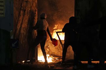 A nationalist throws a petrol canister the Peace Gates in Lanark Way, Belfast during further unrest in Belfast. Picture date: Wednesday April 7, 2021.