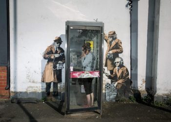 FILE PHOTOS OF phone box which has been surrounded by new Banksy artwork in Cheltenham. 14th April 2014. See SWNS story SWBANKSY; A famous Banksy once valued at a million pounds which "fell" off a wall appears to be for sale on Facebook. The elusive artist created 'spy booth' depicting three 'spooks' snooping on a phone box with listening devices near GCHQ in Cheltenham, Glos., in 2014. But it was reduced to a pile of rubble when builders worked on the wall above the artwork and it collapsed last summer. Building owner David Possee took the bits to the council for safekeeping, but yesterday (Weds) the broken pieces appeared for sale on Facebook.