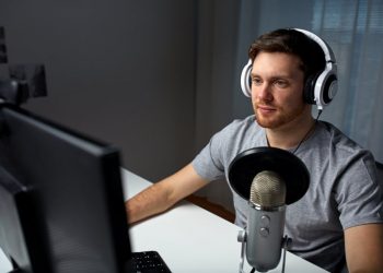 technology, gaming, entertainment, let's play and people concept - happy young man in headset with pc computer playing game at home and streaming playthrough or walkthrough video