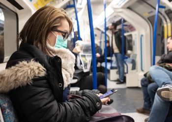 A woman wearing a facemask on the London Underground.