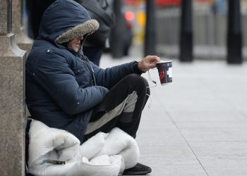 Rough sleeper on street with cup