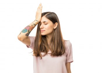 Woman realizing mistake and keeping hand on head over white background